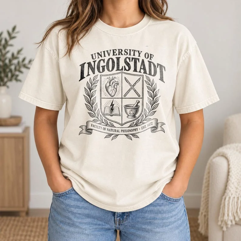 Ivory Comfort Colors Frankenstein shirt with black University of Ingolstadt collegiate crest and botanical details.