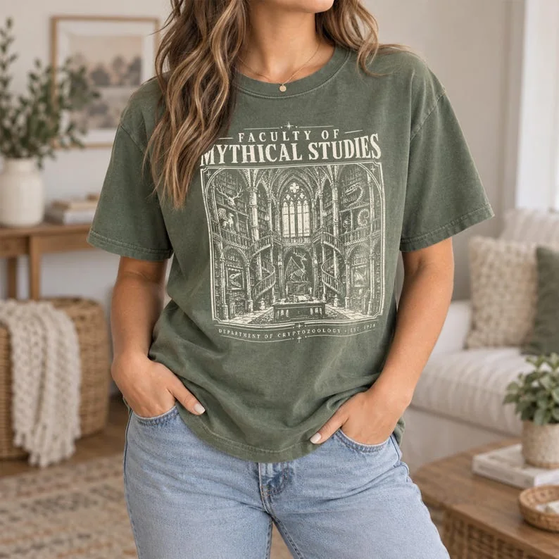 Moss green Comfort Colors Mythical Studies shirt with cream cryptozoology and dark academia design.