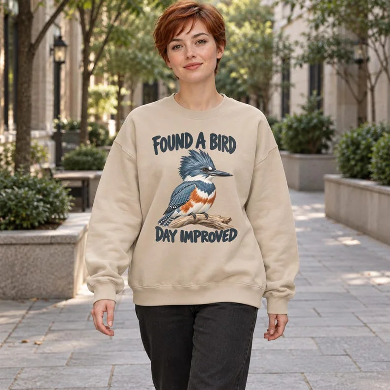 Sand Found a Bird Day Improved sweatshirt on older woman outdoors, with kingfisher illustration and birding phrase.